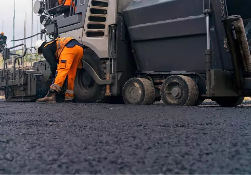 Workers are seen performing road work. BearCat Manufacturing makes the best chip spreaders.